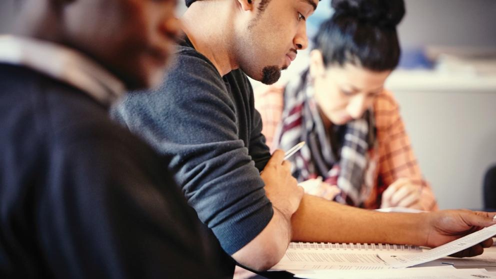 Three students reading literature in a class