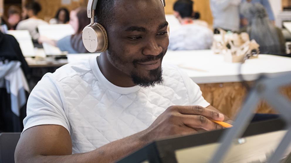 Student wearing headphones using an architects drawing board