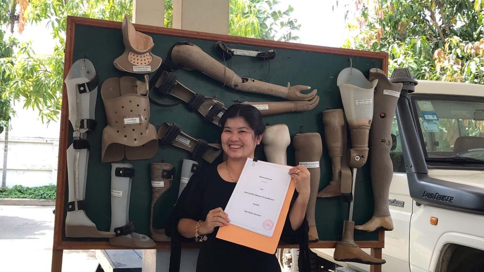 Sisary Kheng holding a certificate with prosthetics behind her 