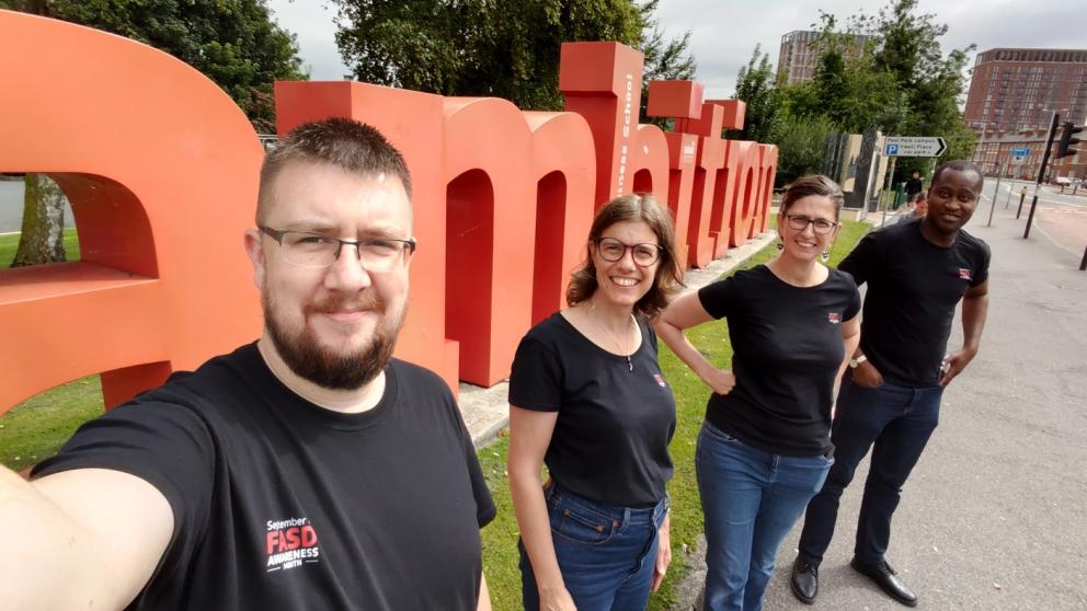 SalfordFASD team stood next to the Ambition sign on Peel Park campus, University of Salford