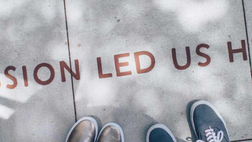 People look at a notice on the floor which says 'Passion led us here'