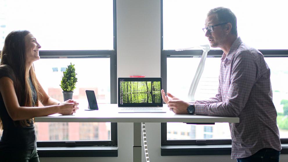 Colleagues using a standing desk