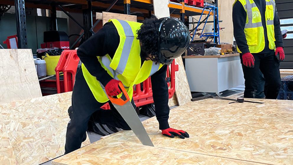 Civil engineering student sawing wood