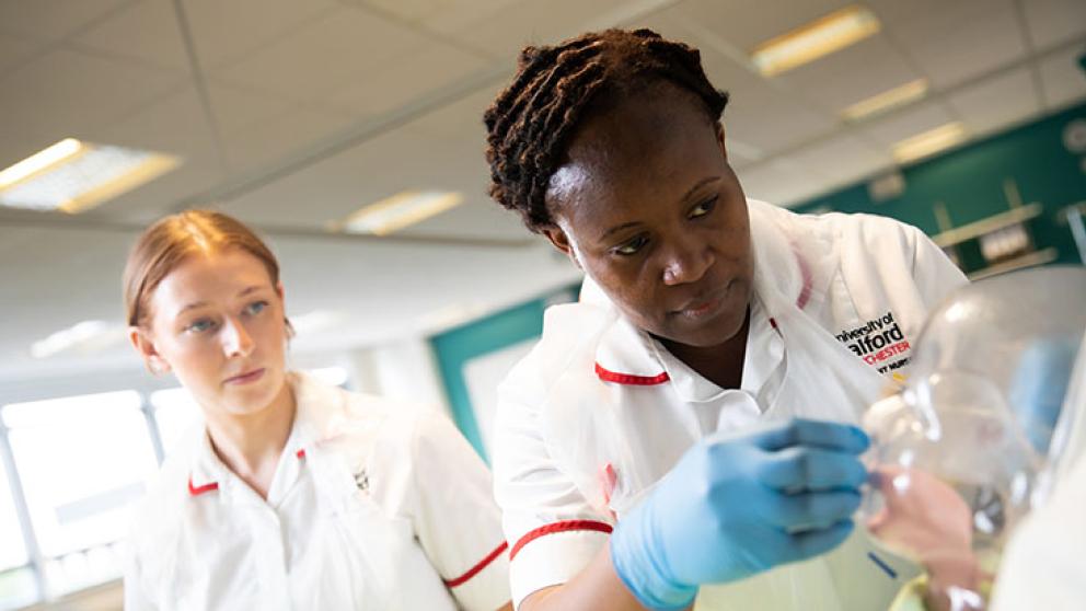 Nursing degree students practise delivering care to a nursing training doll.