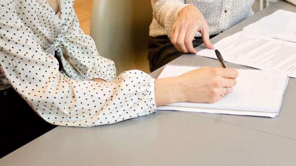 Two people at a desk working with pen and paper