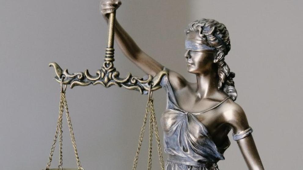 A close-up of a statue of Lady Justice holding a set of balanced scales, symbolising fairness and the legal system.