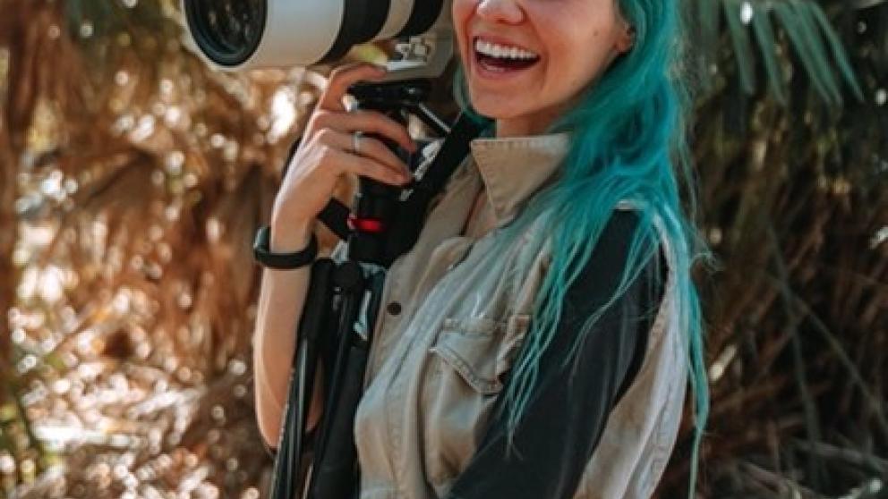 A woman is smiling and holding a film camera