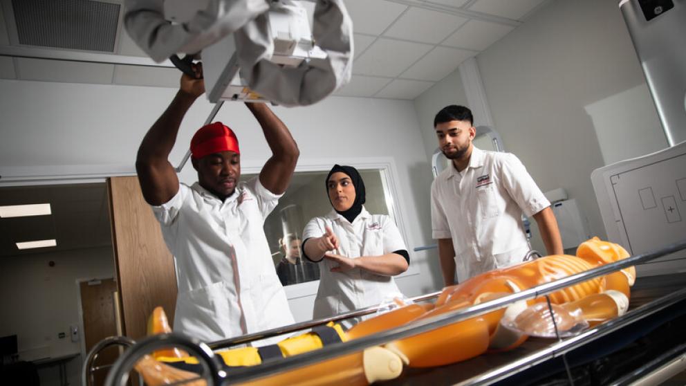 Three medical students working with a mannequin in the Centre for Medical Imaging at the University of Salford