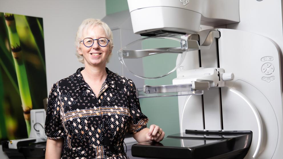 Dr Claire Mercer standing in a lab next to a mammography machine