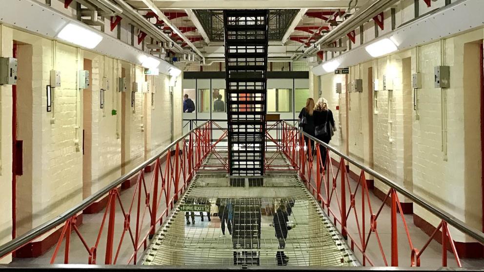 Photograph of the inside of a prison with people walking around. 
