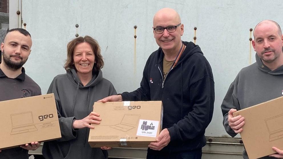 Four people holding laptop donation boxes