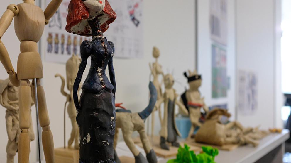 Animation character models and a wooden mannequin displayed on a desk in a studio 