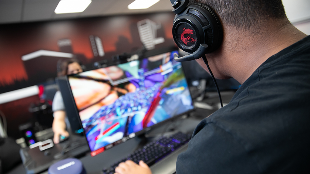 Student wearing headphones, using a workstation in the Esports Suite, Salford Business School