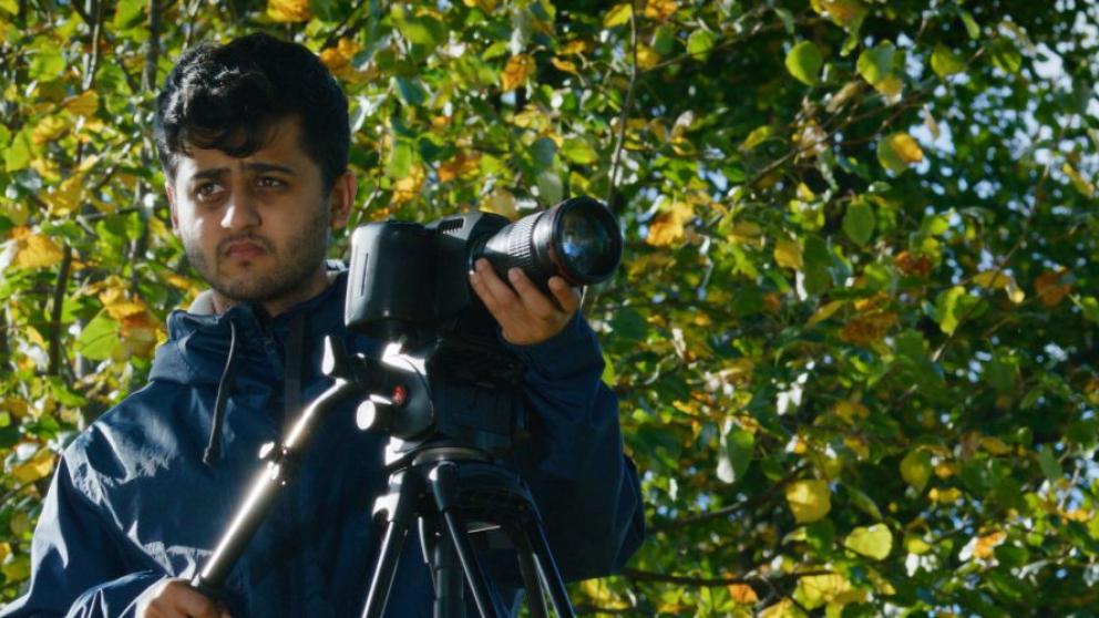 A man pointing a camera and searching for what to take an image on.
