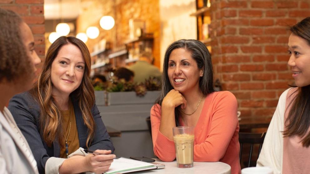Four women sat talking around a table