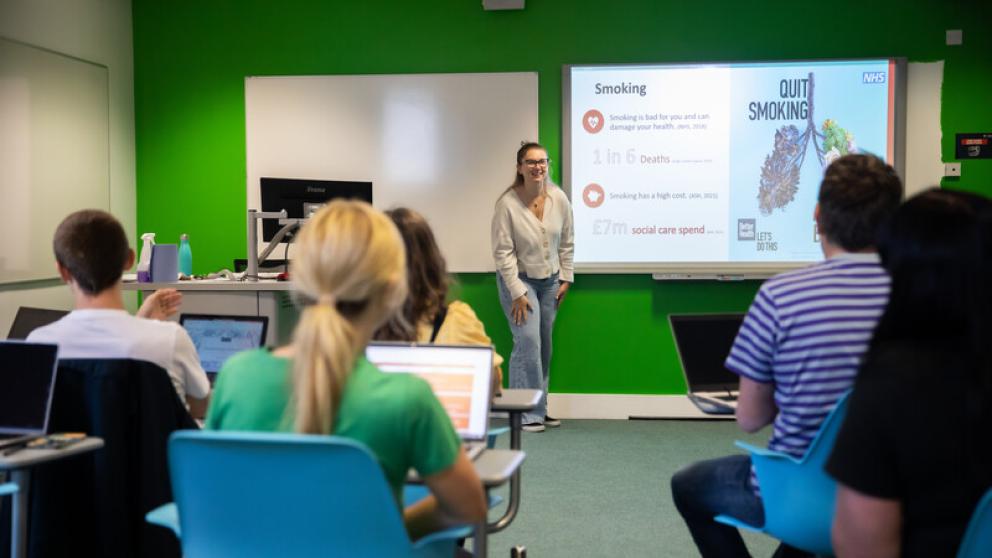 Image shows classroom with students hosting a presentation