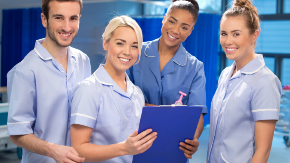 4 medical people stood in scrubs holding a clipboard