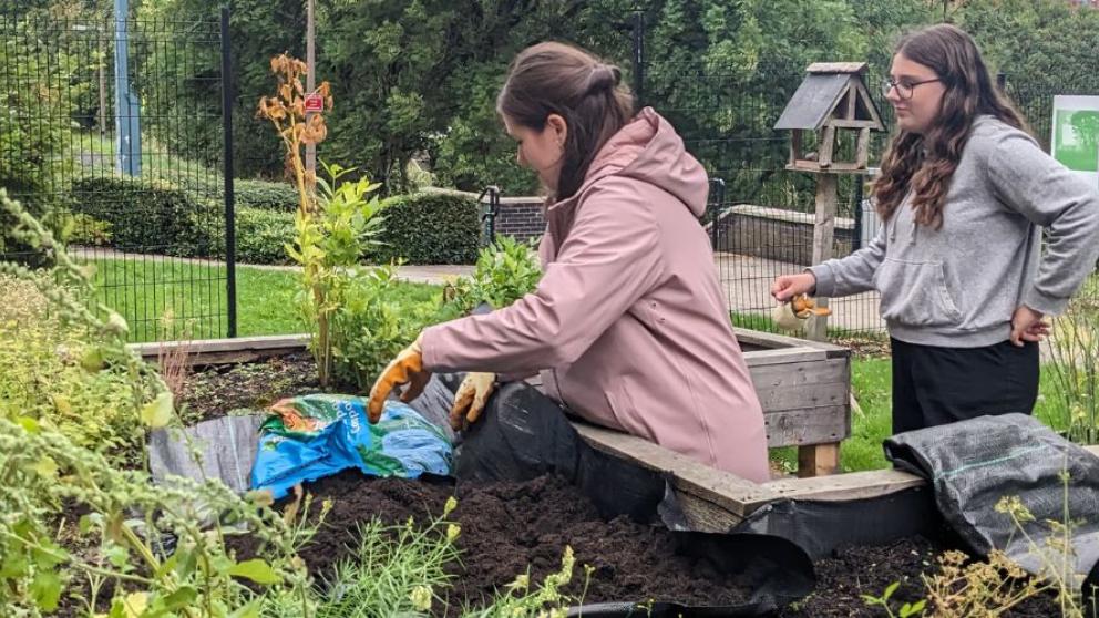 Two members of staff working in a garden space