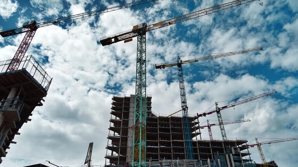 Skyline of five cranes and partly built tower blocks with scaffolding