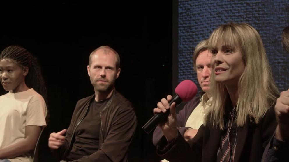 Szilvi Naray speaking with a microphone at the Dead Man event