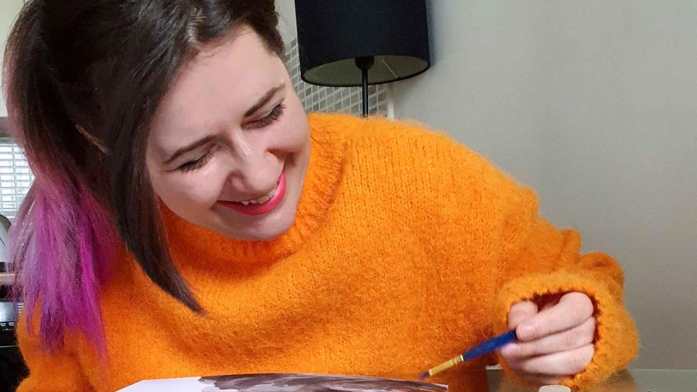A lady in an orange sweater sketching