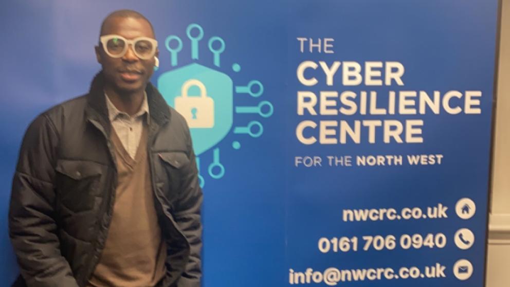 A male student in front of a sign for the Cyber Resilience Centre