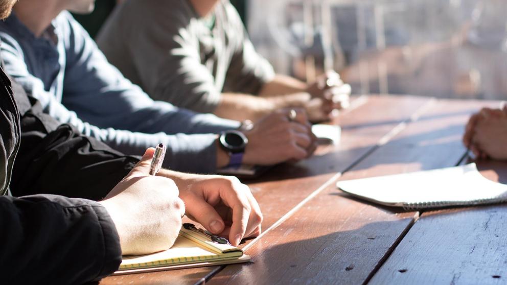 Four students say outside making notes on paper