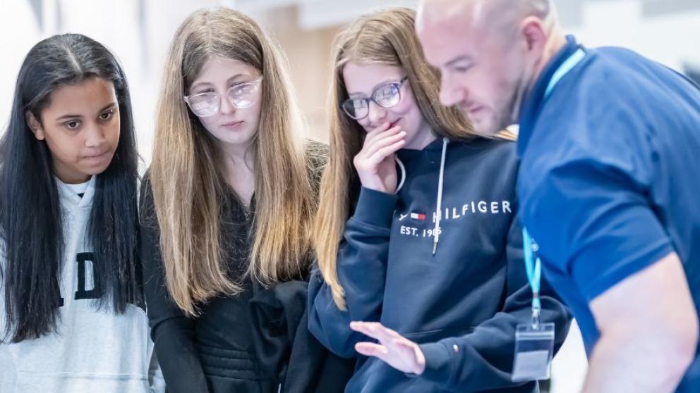 Four students and one supervisor looking at laptops
