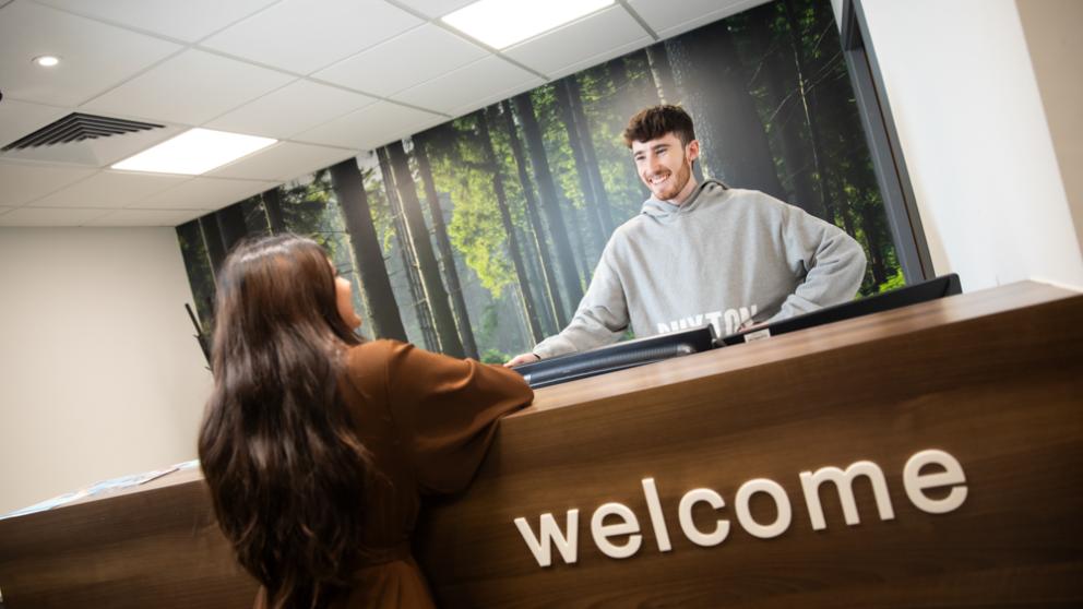 Male student greets female student in the Counselling Suite reception.