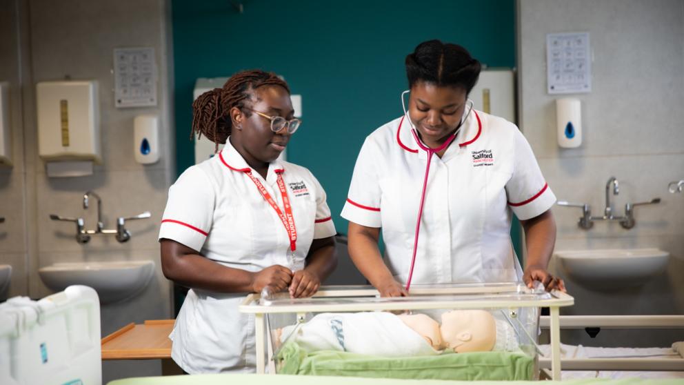 Two female student midwives conducting new-born checks.