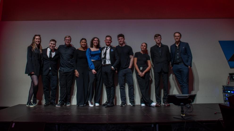 A group of people stand on stage at an awards show