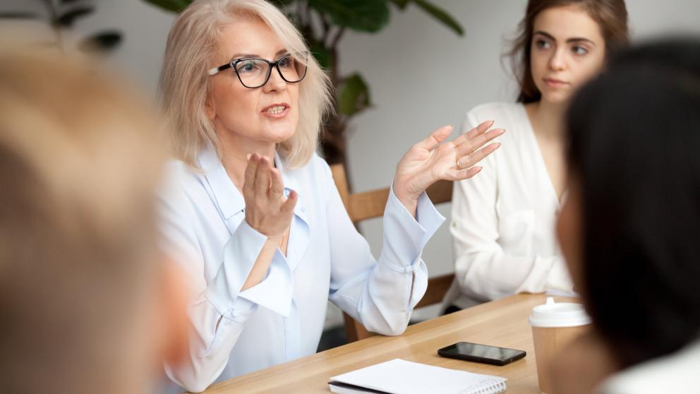 A woman gestures with her hands in a meeting