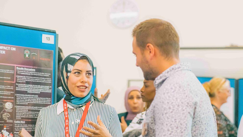A researcher presents a poster of her research to a colleague