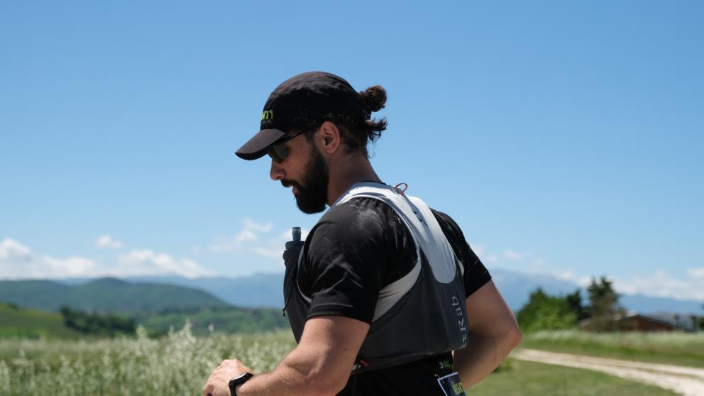 A man wearing a hat runs alone in an Italian field 