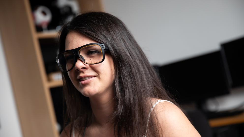 Female student wearing eye-tracking glasses in the psychology lab observation room.