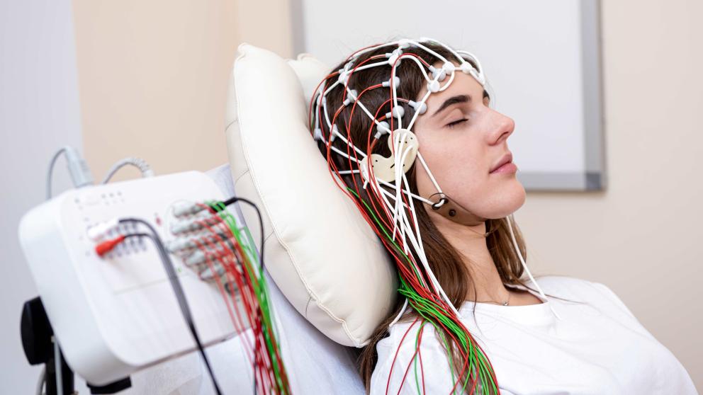 Woman lying in bed wearing EEG equipment 