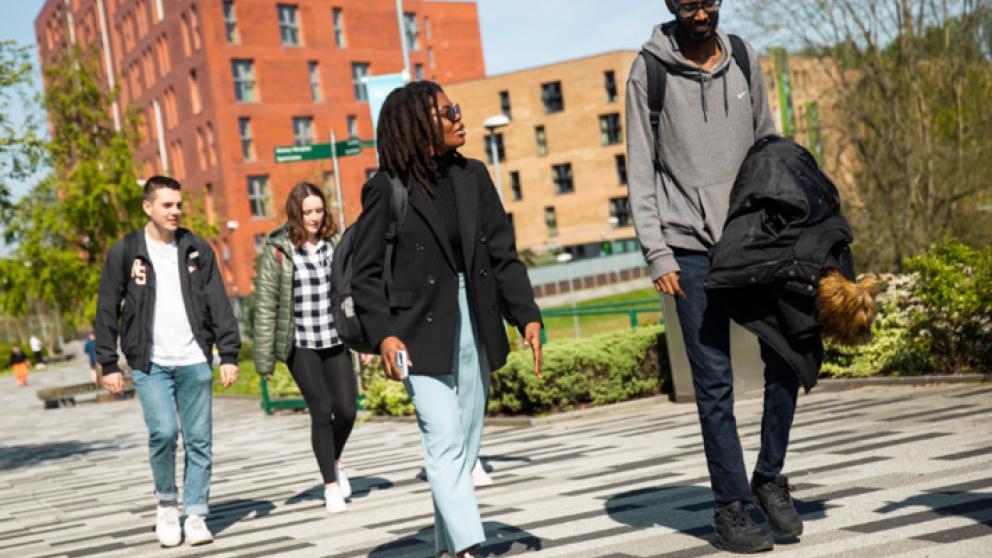 A group of students walking in front of Peel Park Quarter student accommodation