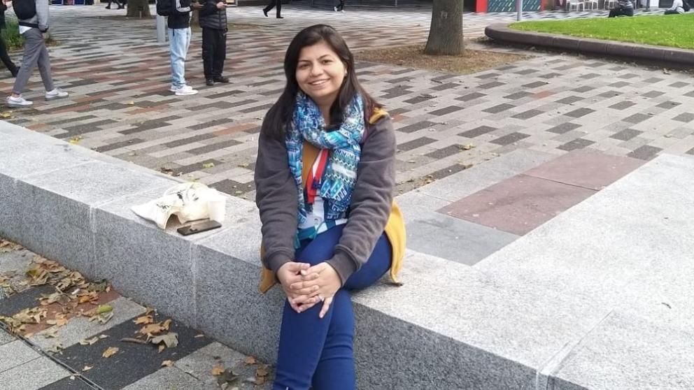 A female student sat crossed legged on our Peel Park campus in front of the Clifford Whitworth Library