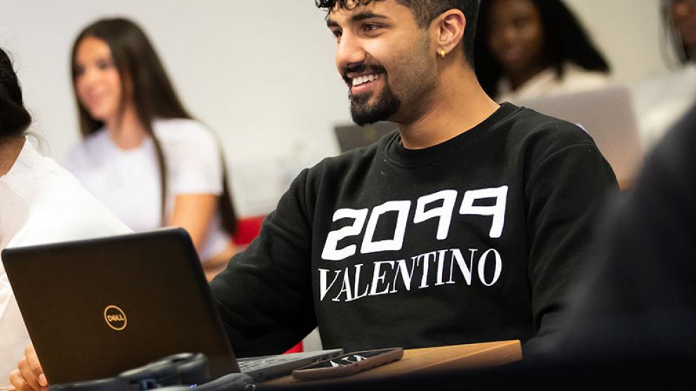 Student with open laptop in classroom