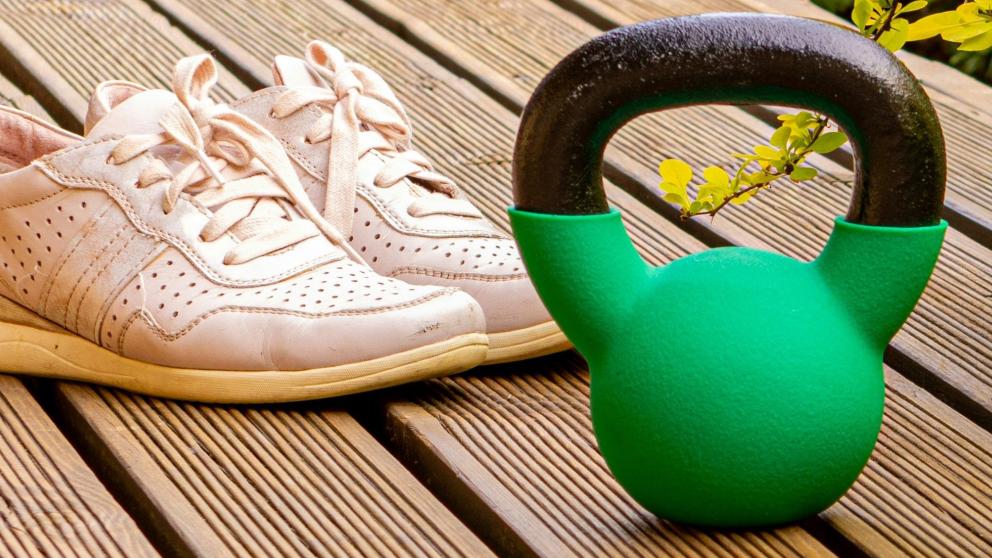 A kettlebell and a pair of trainers on decking