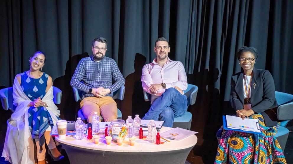 Four alumni smile at the camera