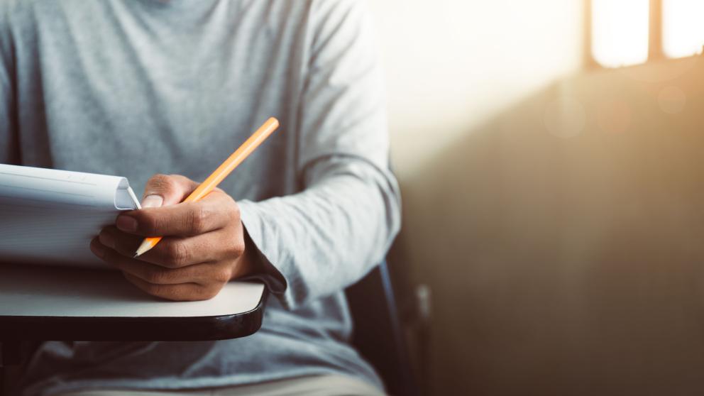 Male student holding a pen and paper 