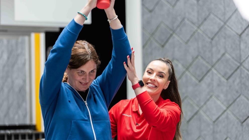 Ashley helps a female colleague with a strength routine 