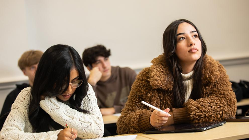 Two students taking notes in a lecture