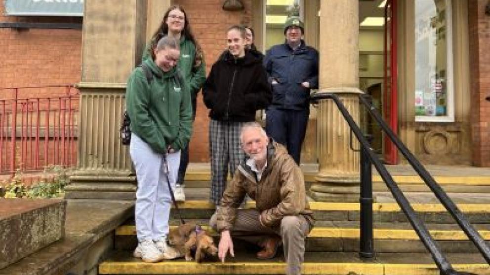 A group of people and a dog on the steps of Salford Museum and Art Gallery entrance