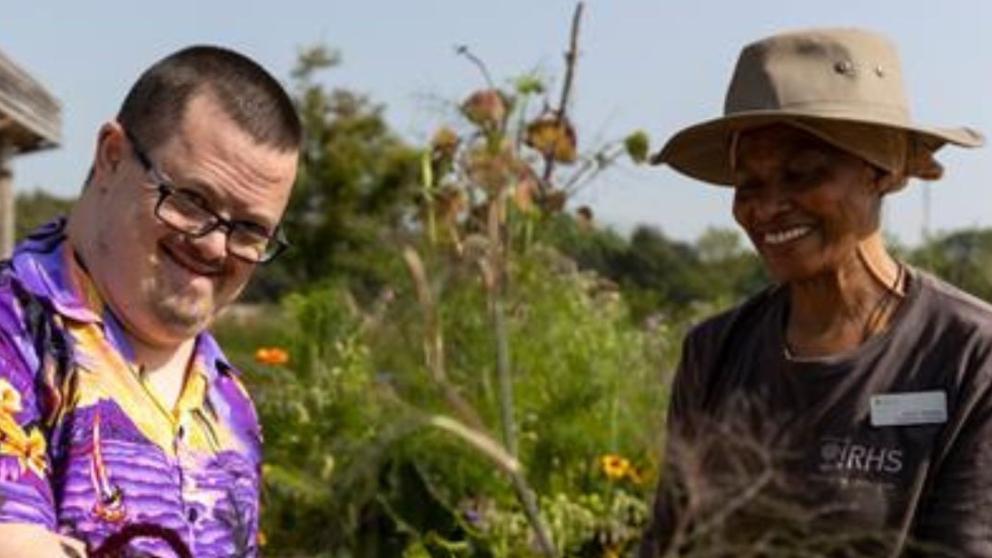 A man and a woman enjoy the community garden in sunshine