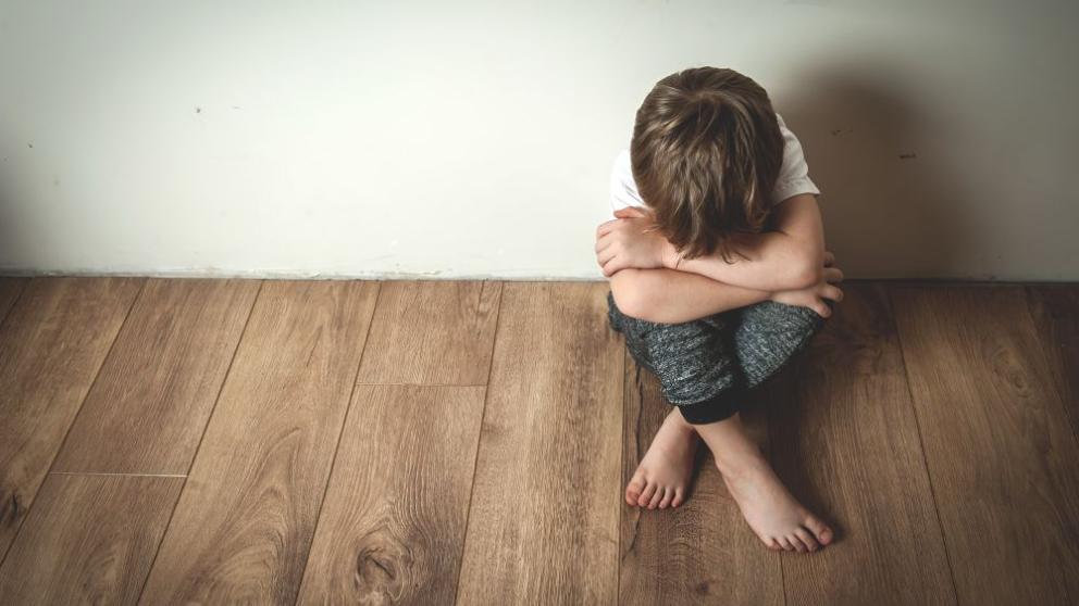 Child sitting on floor with head in hands