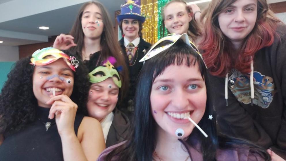 A group of students taking a selfie with mardi gras masks on