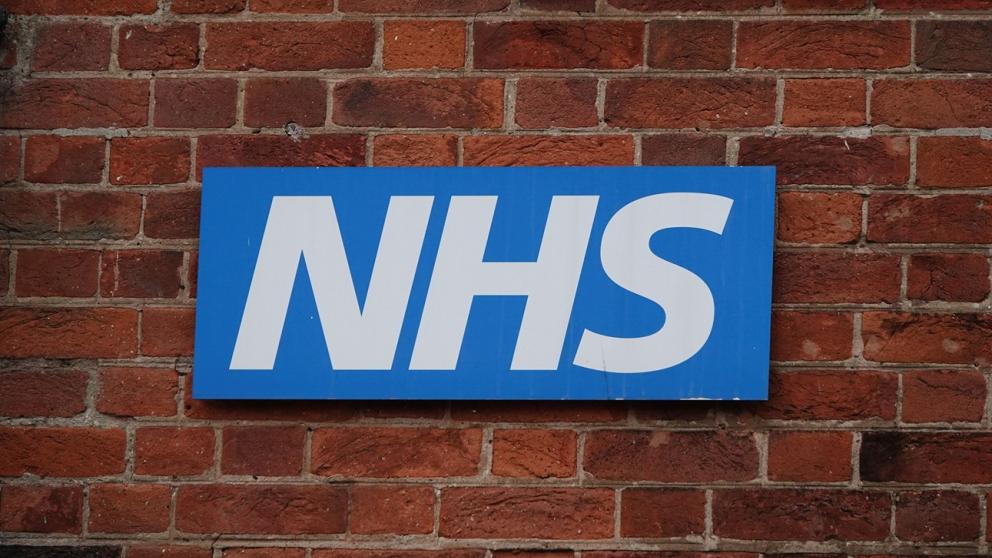 NHS logo on a brick wall