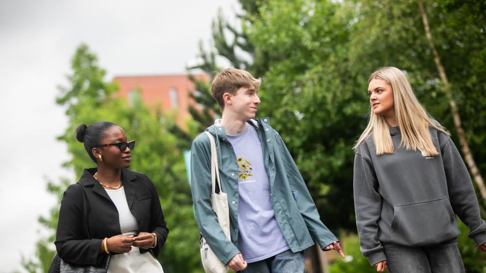 Three students walking on campus talking